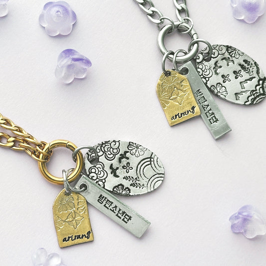 Silver and gold charm bracelets with engraved tags on a white background